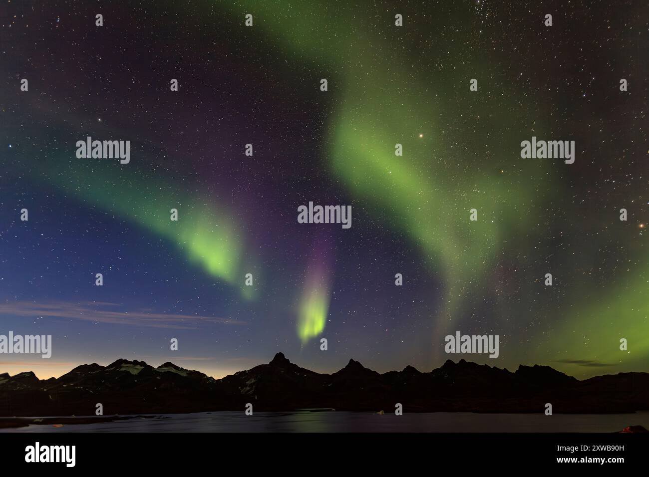 The Northern Lights dancing over the snowy peaks of Greenland