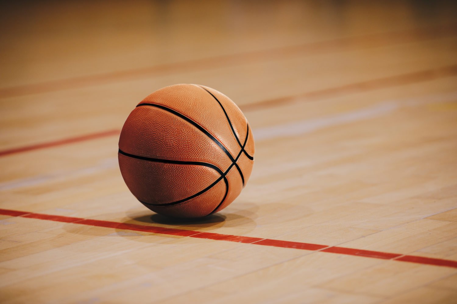 A basketball sitting on a tournament court featuring the NCAA logo