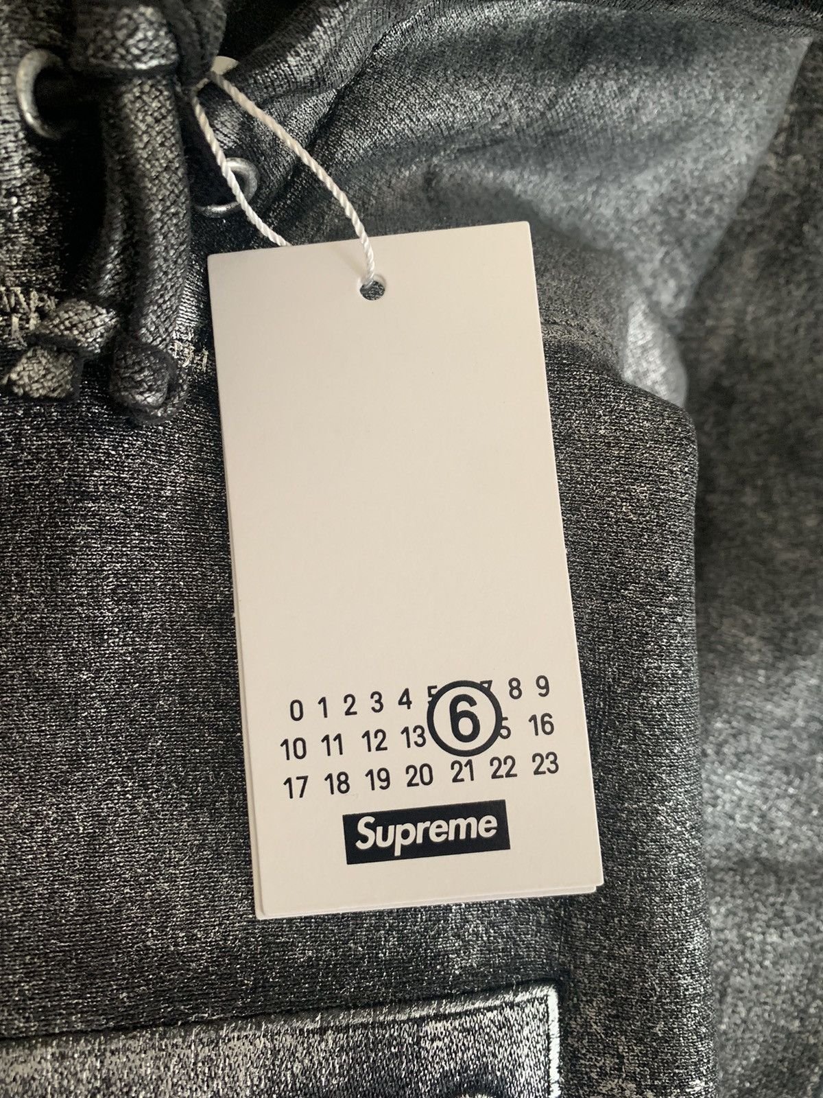 Detailed view of the Maison Margiela numerical tag on a Supreme garment
