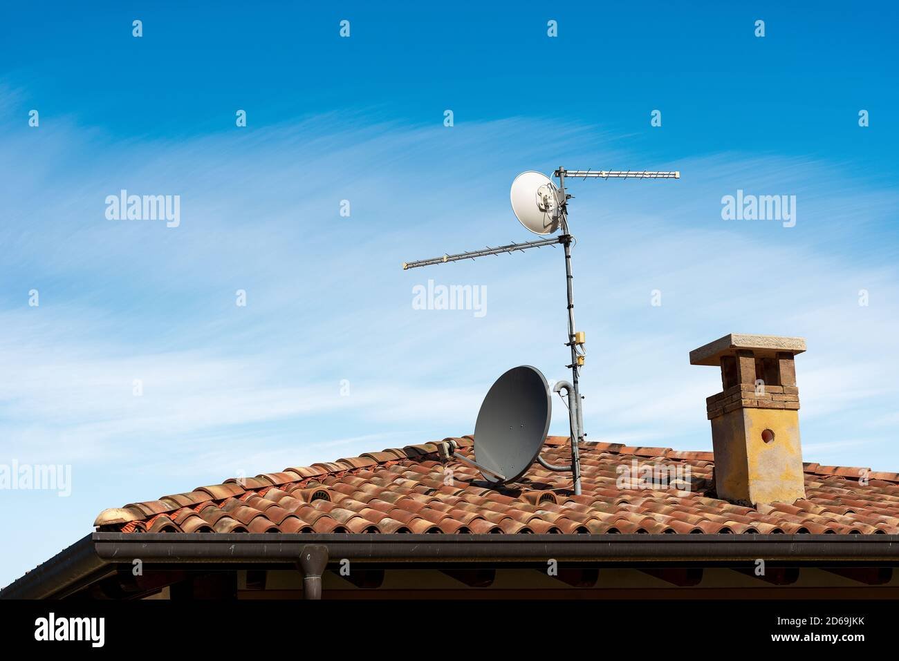 A modern satellite dish installed on a residential roof against a clear blue sky