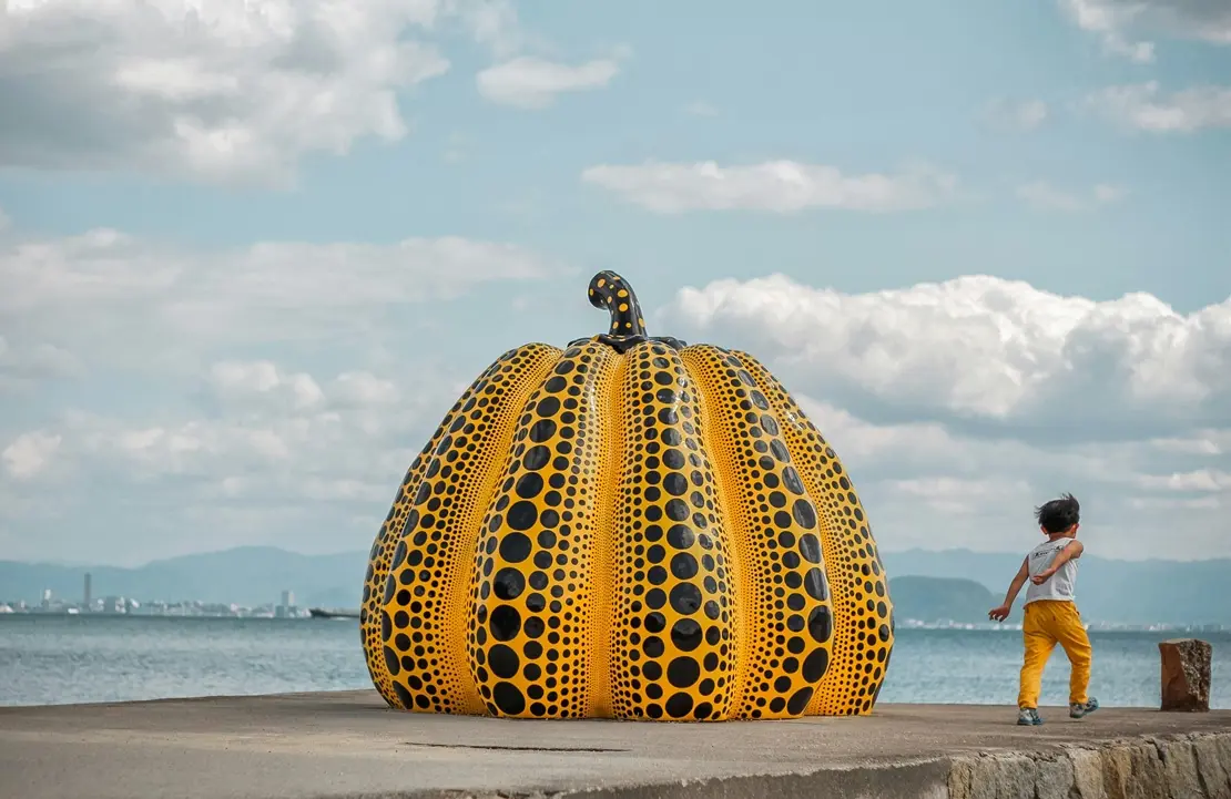 A large yellow and black polka dot pumpkin sculpture by Yayoi Kusama